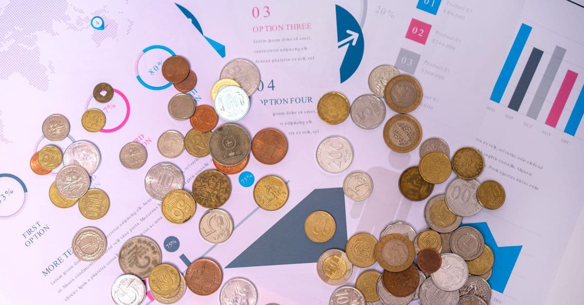 Münzen liegen auf Finanzdokumenten mit Diagrammen und Kurven.