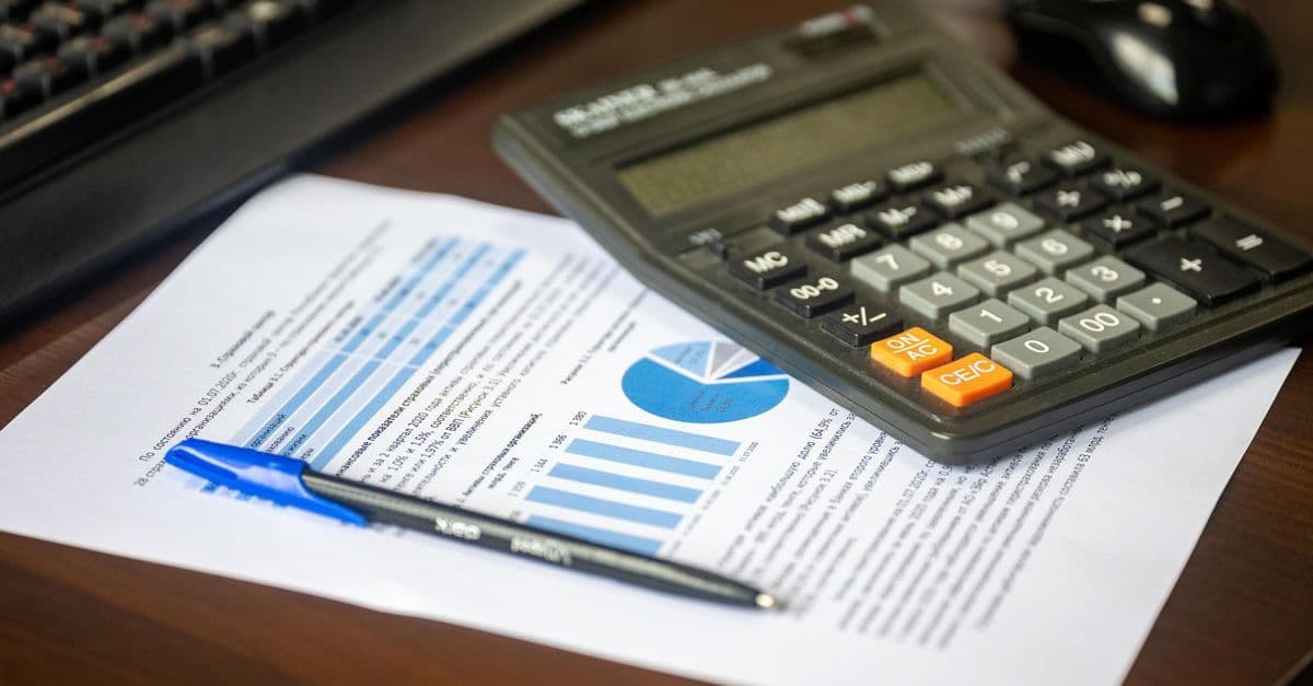 Schreibtisch mit Taschenrechner, Finanzbericht und Stift für finanzielle Berechnungen