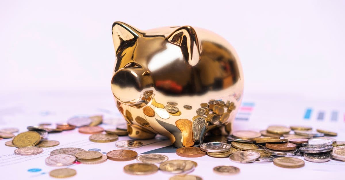 Goldenes Sparschwein auf Finanzunterlagen mit verstreuten Münzen