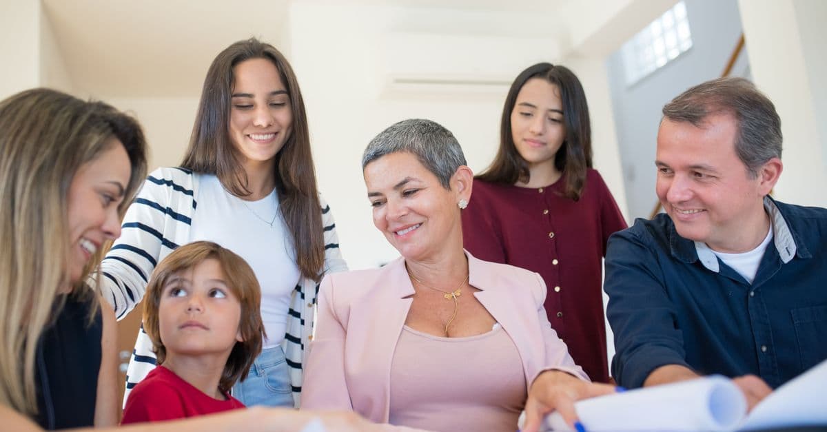 Familie bespricht mit einem Makler an einem Tisch Immobilienunterlagen im Innenraum